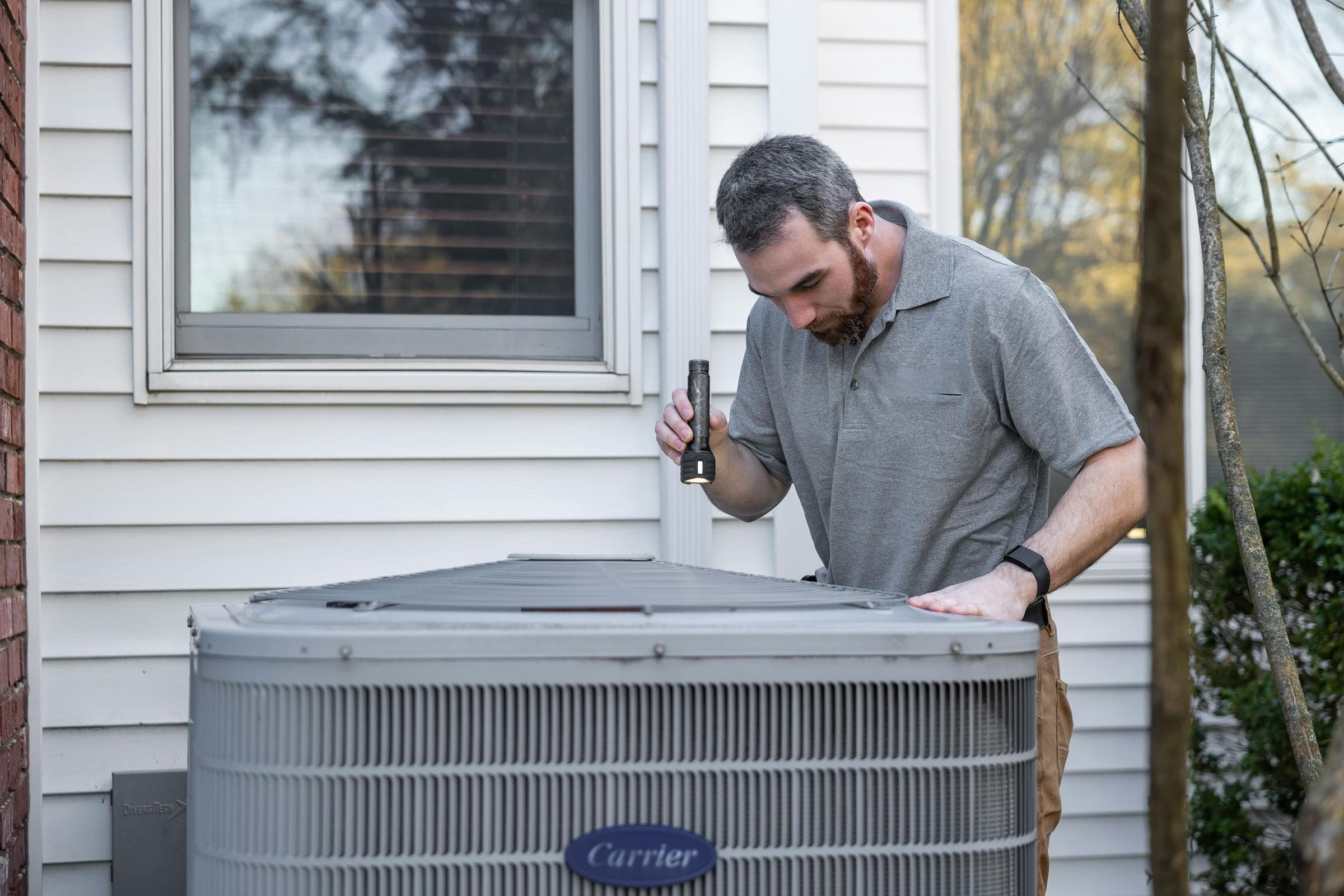 HVAC technician inspecting an outdoor air conditioning unit during a AGC Heating & Air service call